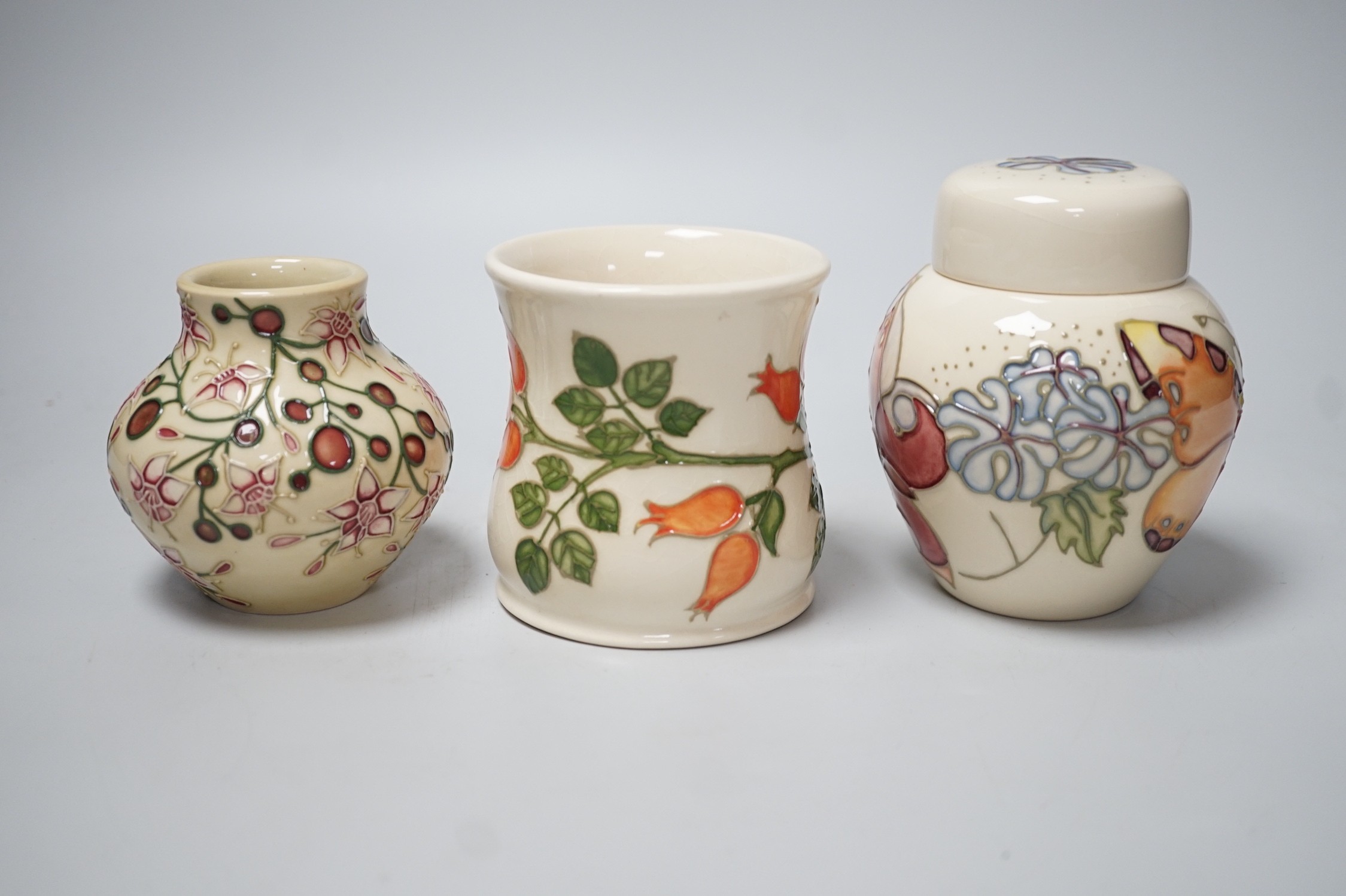 Three boxed Moorcroft pieces; Rose Hip cup, Butterfly jar and cover, and a Fuchsia vase, tallest 11 cm